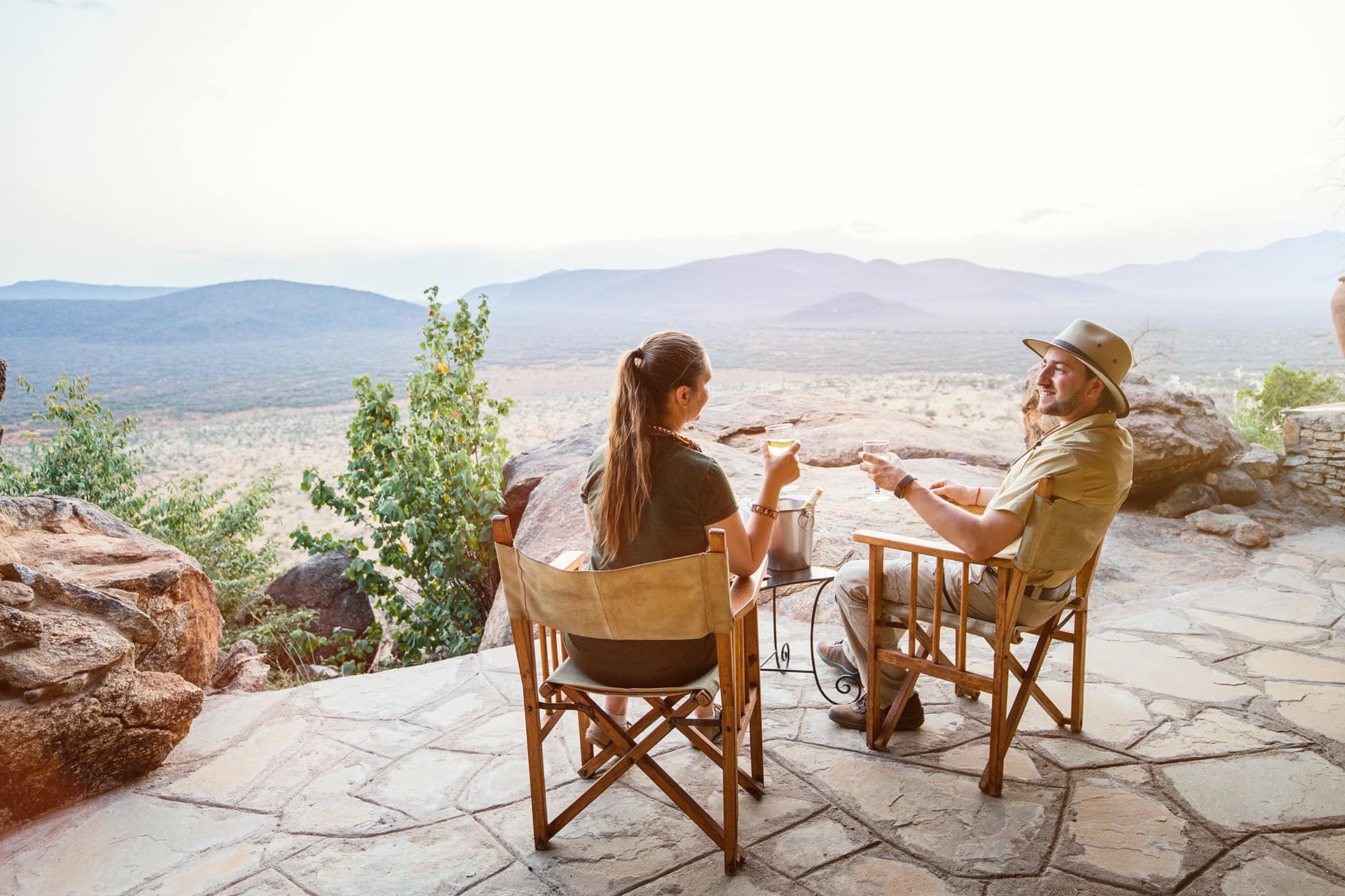 A couple having a cup of coffee at a scenic lodge viewpoint with panoramic views of Tanzania’s landscapes.