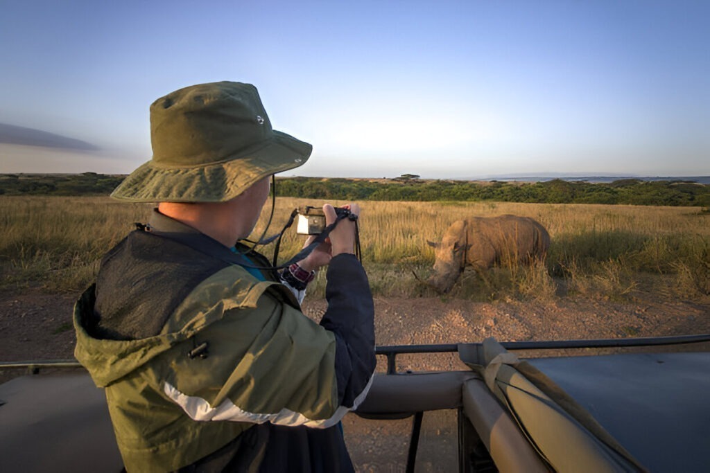 A photographer taking a close-up shot of a rhino during a Tanzania wildlife safari.