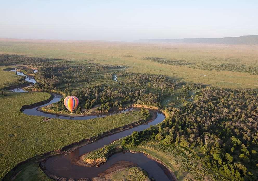 A hot air balloon floating over a winding river in the Serengeti, providing an unmatched aerial safari experience.