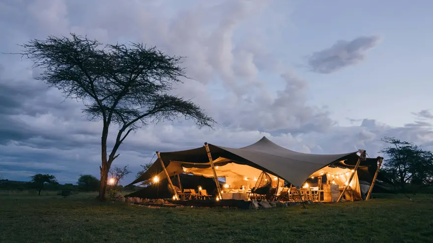 Stunning luxury tented safari camp glowing with golden lights, offering an exquisite and immersive wilderness experience in Tanzania.