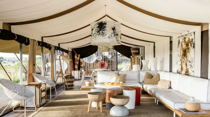Beautiful luxury safari living room with comfortable couches, a stylish table, and traditional handcrafted African chairs, offering an elegant and cozy safari lodge experience.