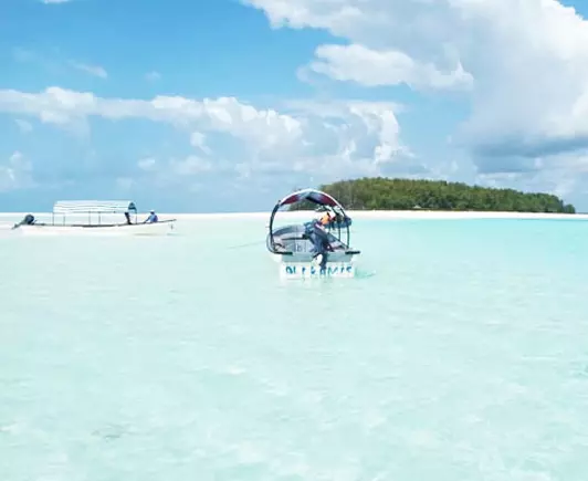 Two wooden boats sailing towards Mnemba Island in Zanzibar, surrounded by turquoise waters.